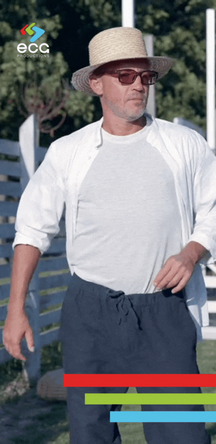 A confident man is filmed in a dolly shot as he walks through his backyard, emphasizing the fluid motion and character-focused framing created by dolly grips.