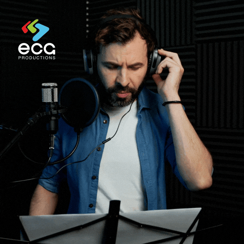 A White man in a blue shirt with a beard and mustache records a voiceover, emphasizing the vocal performance and expertise of voiceover artists.