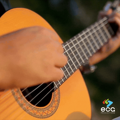 A musician strums an acoustic guitar in a professional music studio, capturing the raw creativity behind original music composition.