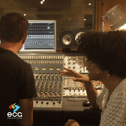 A music producer sits behind a soundboard, bobbing their head to the beat, fully immersed in the creative process of original music composition.