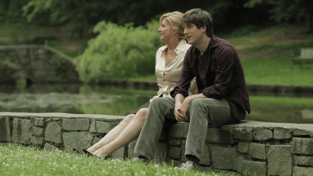 younger man sitting on wall with older woman.