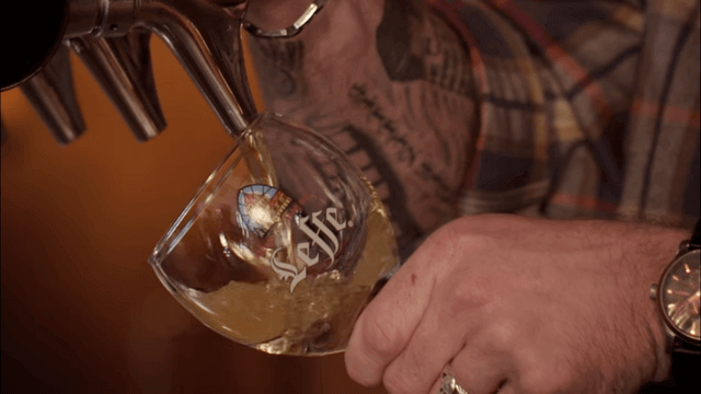 A bartender pours beer from a draught perfectly.