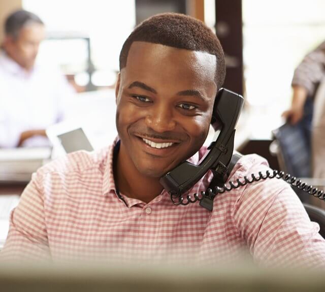 31050179 - businessman on phone at desk with meeting in background