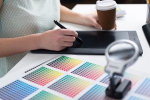 person working on tablet with color grade chart beside them