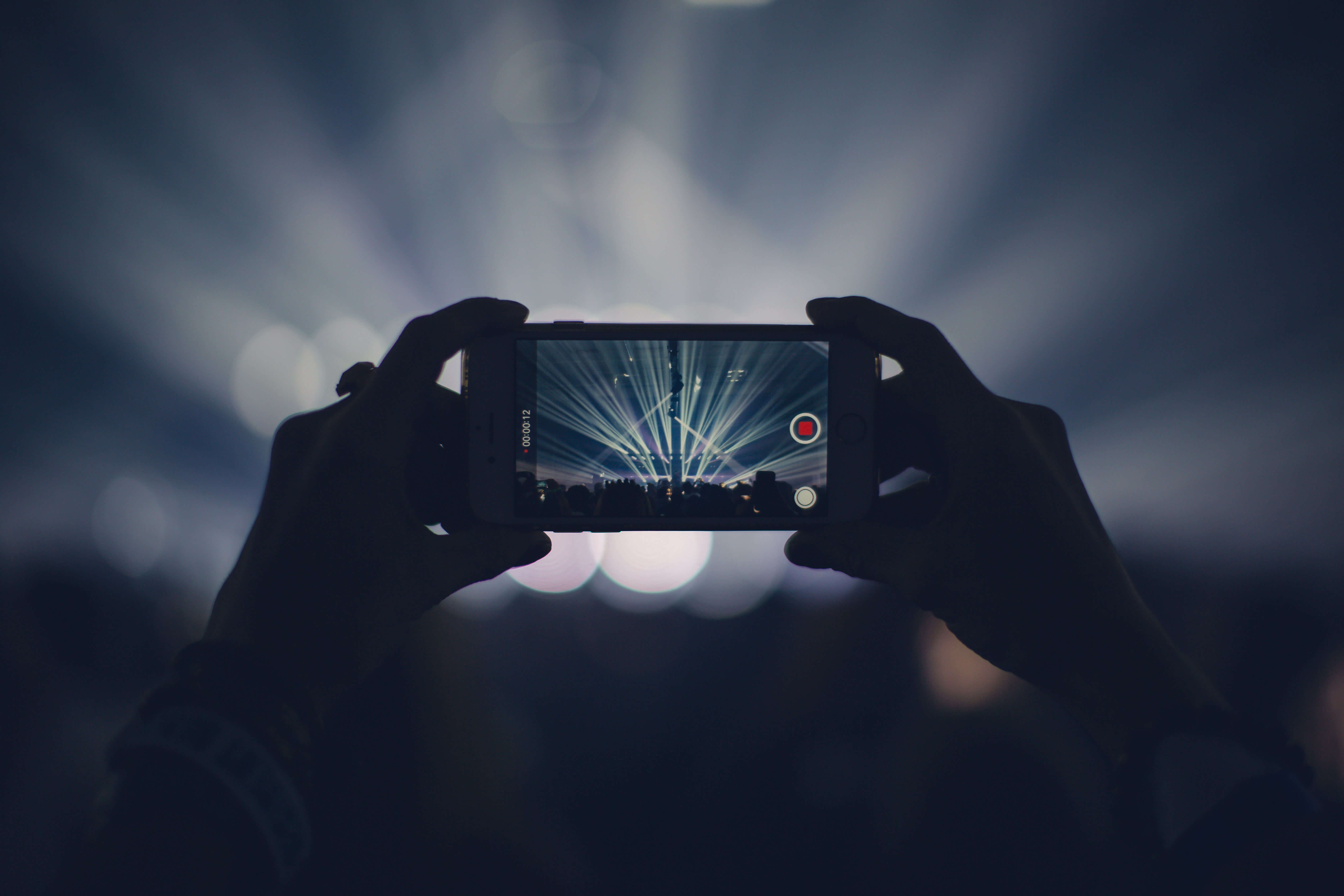 Branded content creator recording concert with smartphone.