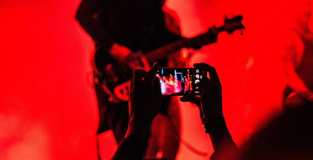 Person at a concert taking video with their cell phone.