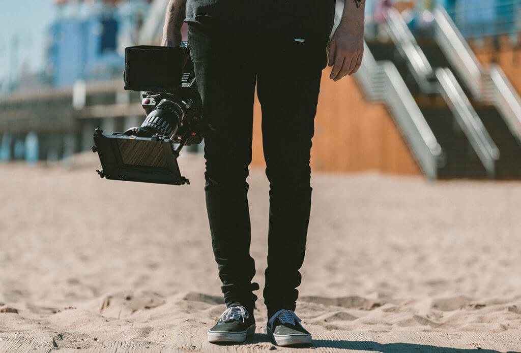 A man stands with a video camera ready to be a go-getter