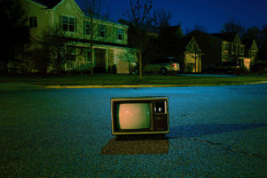 A television sits in the middle of a neighborhood street.