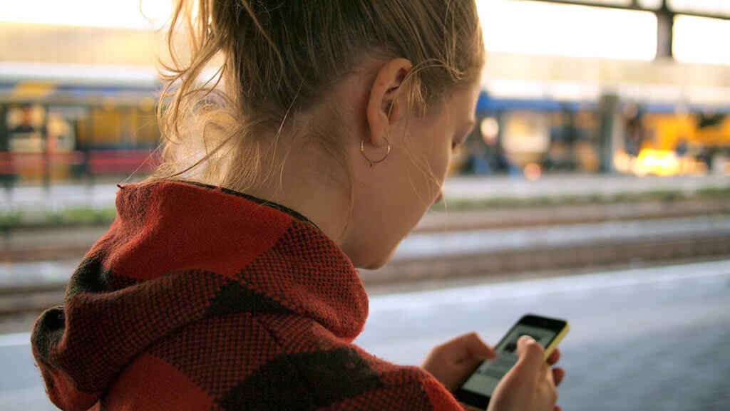 A young woman networks with someone via instant messages on her phone.