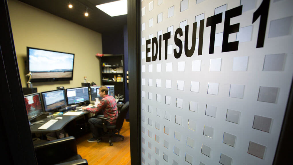 A man video edits in a post-production film editing suite while saving with Georgia tax credits and tax incentives.