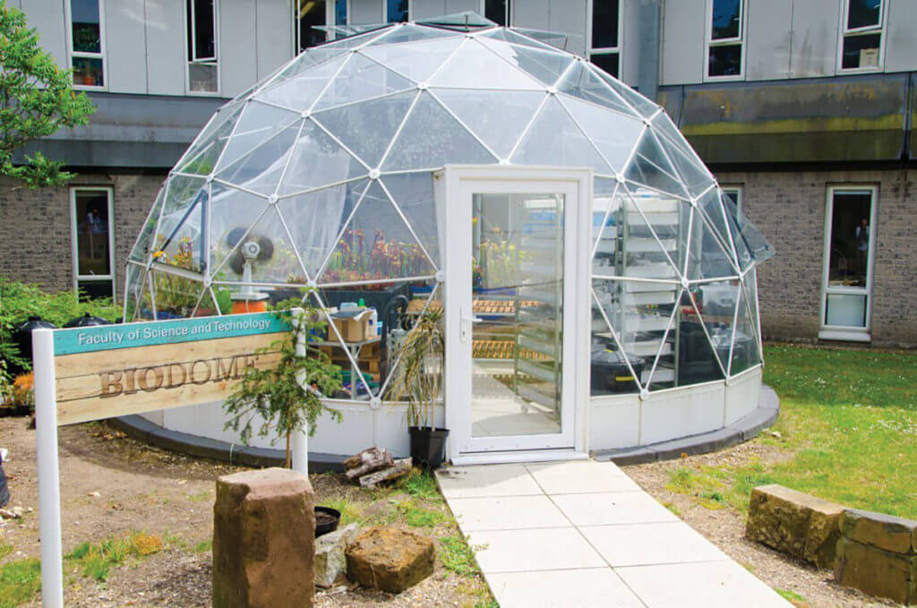 A fully contained biodome sits just outside a university building, symbolizing a scope of work that has everything it needs to avoid a promise of "next time."
