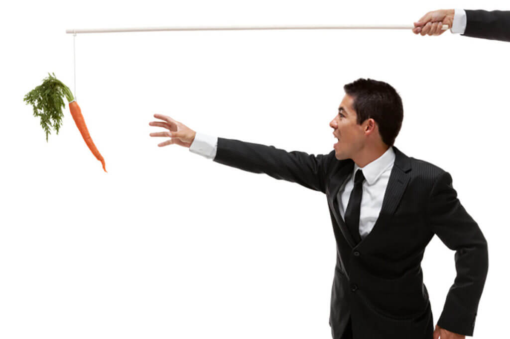 A business or sales man is reaching for a carrot hanging from a stick which indicates that the client is managing expectations.