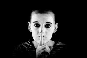 A mime showing the "silence please" sign.