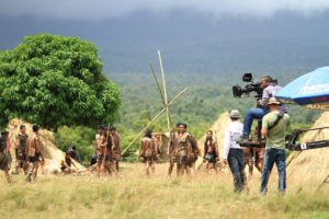 A camera crew films on location as a tribe sets up new stick home and tipi locations.