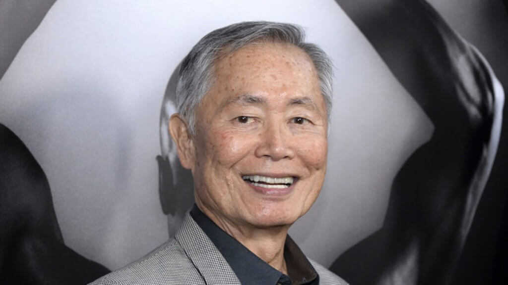 George Takei in a suit smiling at an event.