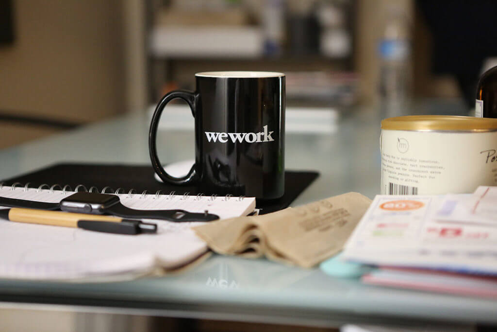 A black coffee mug with the words "We Work" stenciled in white.