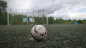 A soccer ball sits on a muddy field.