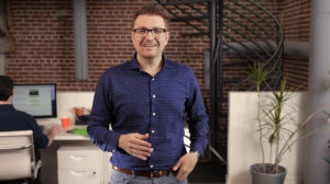 A man in a blue shirt explains the benefits of an Any Lab Text Now employer account.