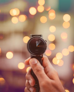 Someone holds up a fancy wrist watch with spinning hour and minute hands indicating that time is money.