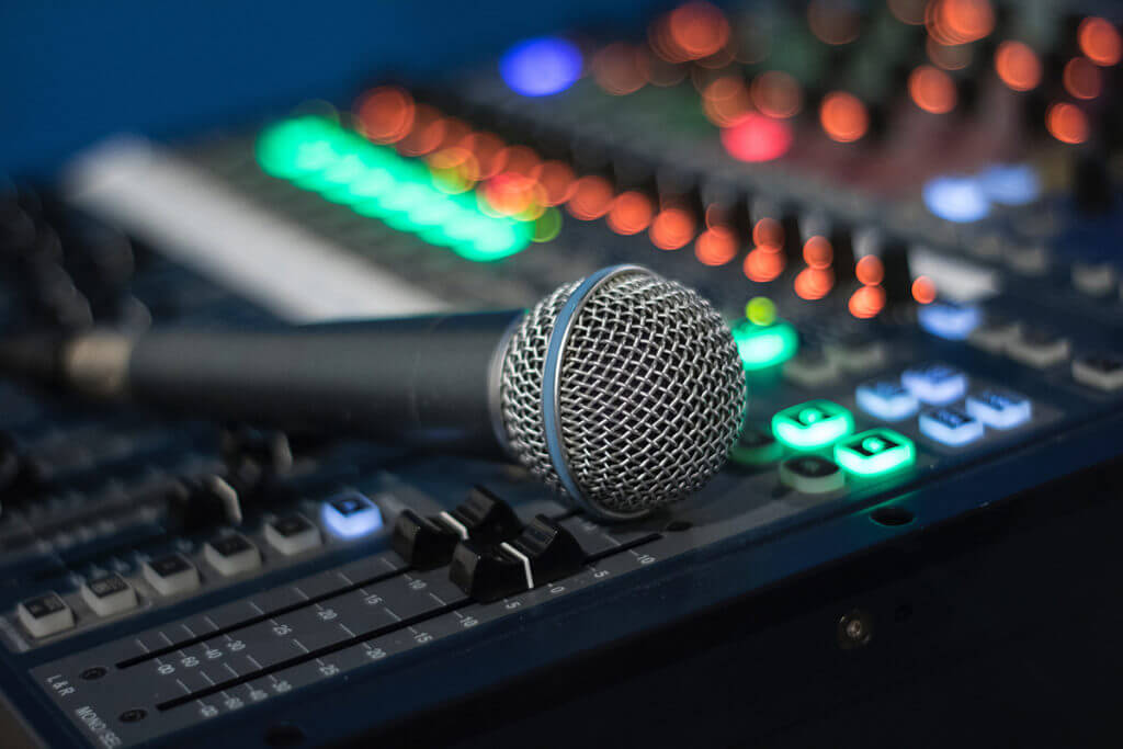 A microphone rests on top of an audio engineer sound board.