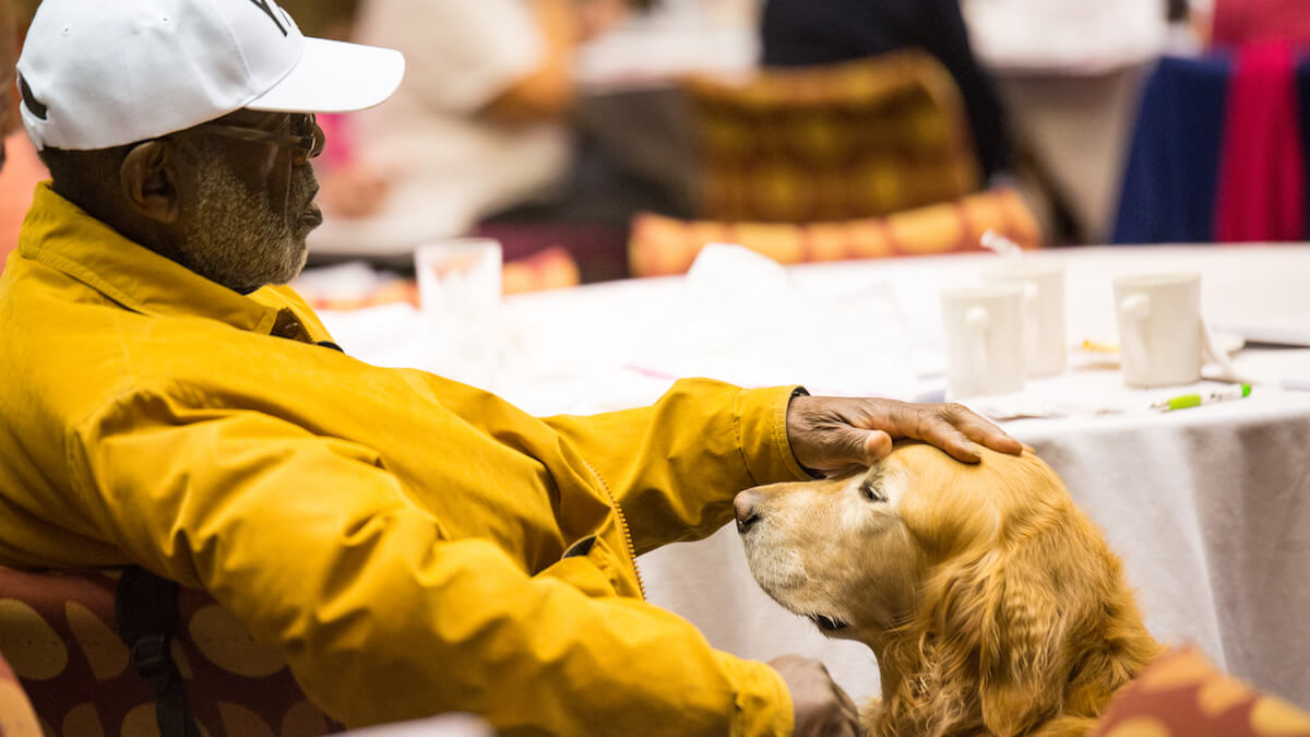 A can-do MS man sits with his dog in this behind the scenes photograph.