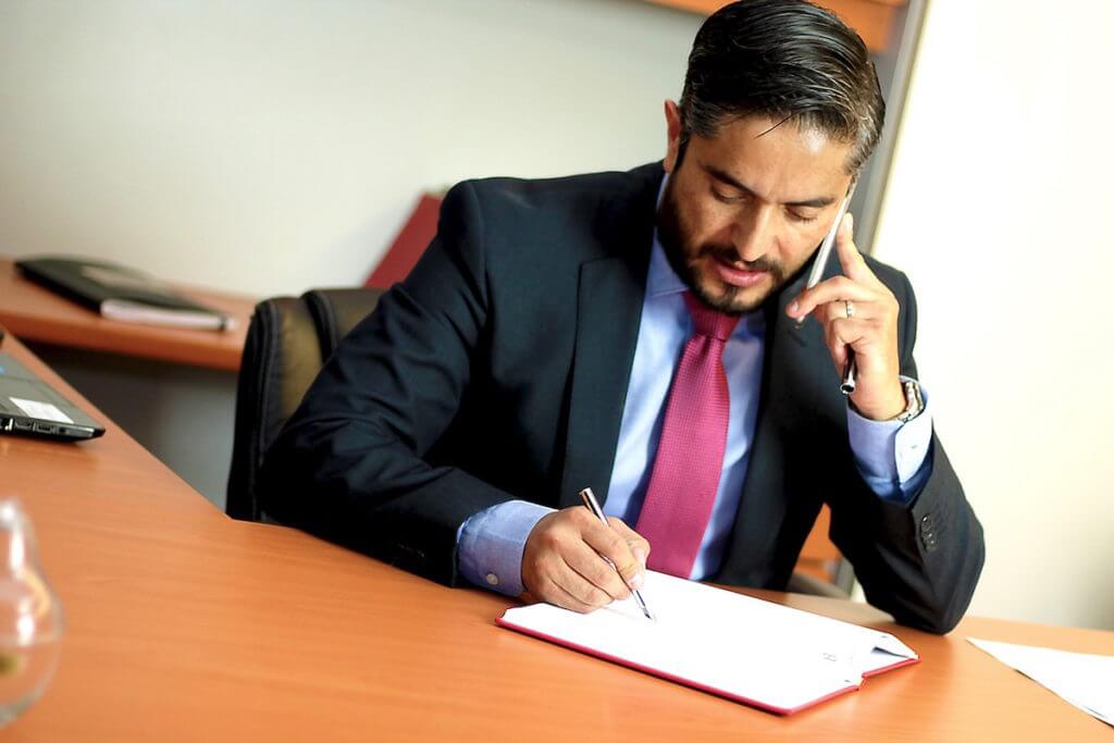 A man sits at a desk writing an effective contract.