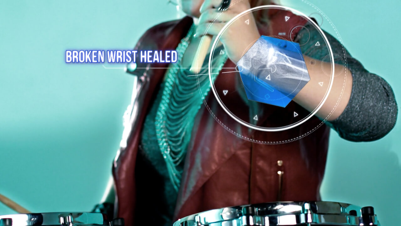 Closeup of a woman drummer in a red vest with a broken wrist healed.