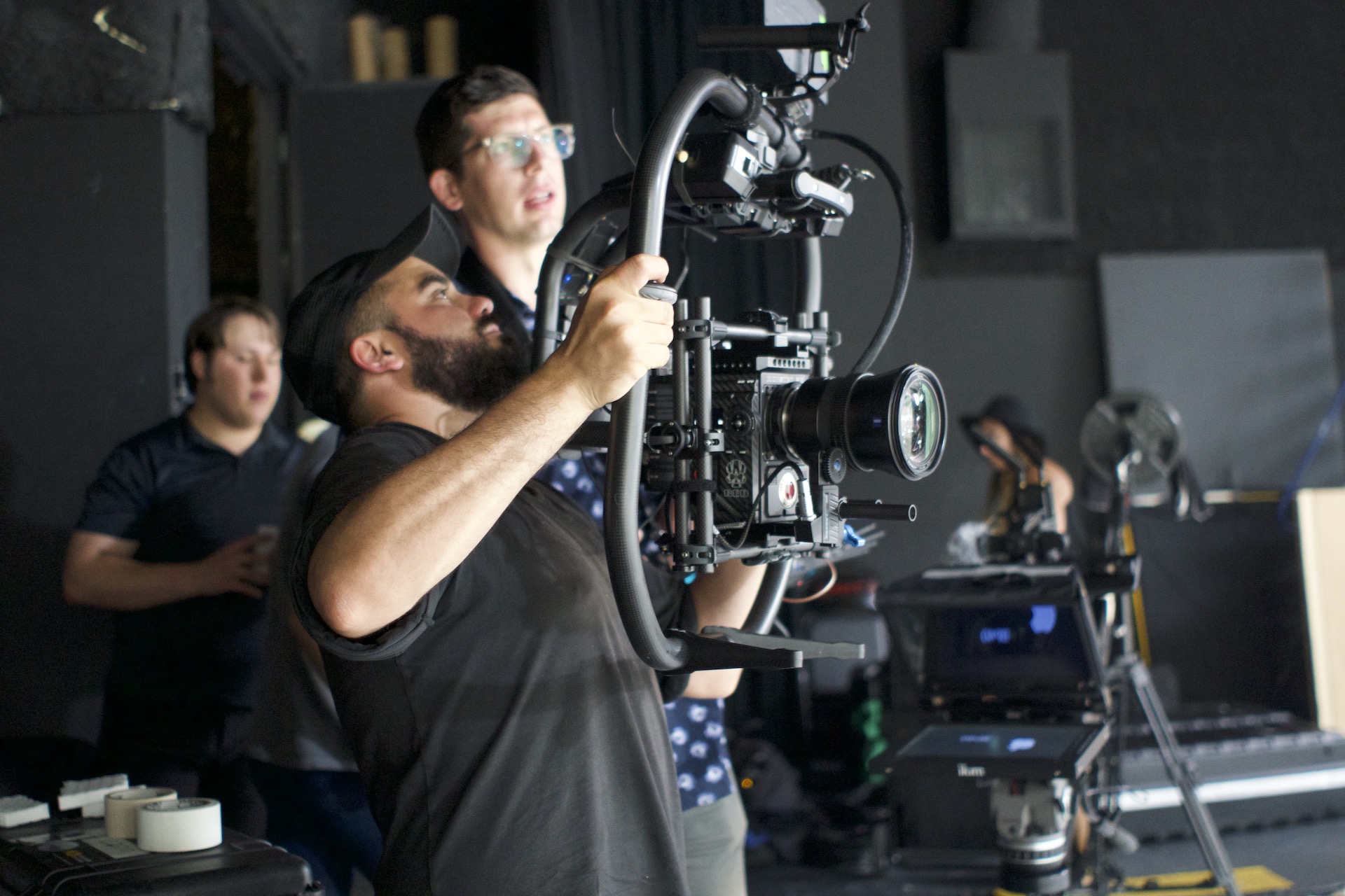 A man assists production by holding a camera and gimbal.