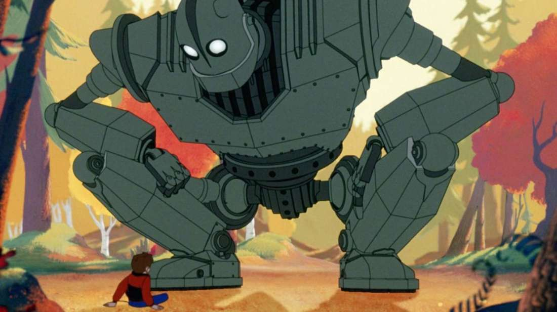 The iron giant squats down and faces a boy.