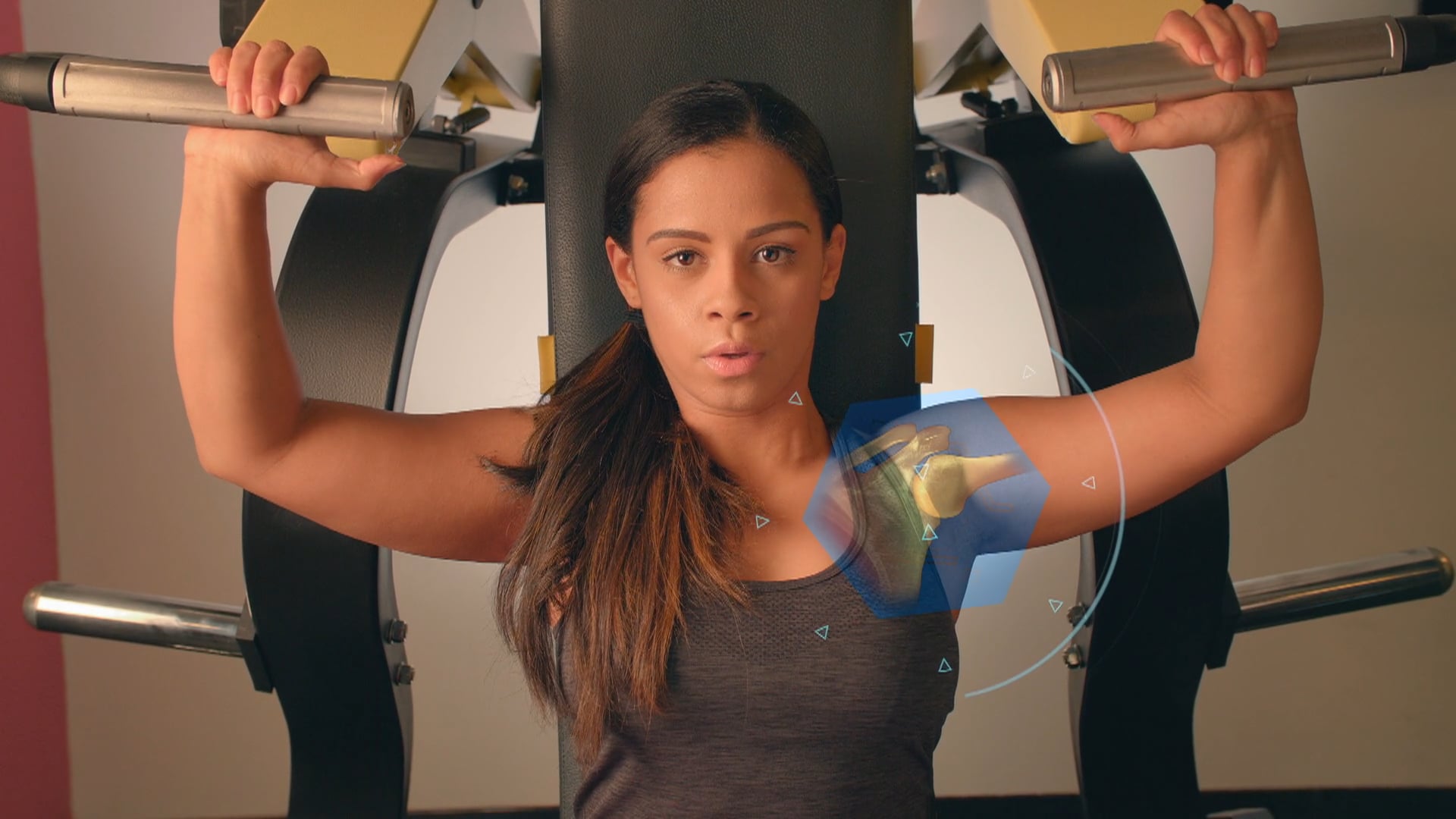 A woman stares into the camera while performing a no-excuses bench press.