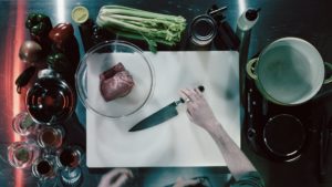 A bird's eye view of a chef grabbing a knife on a cutting board.