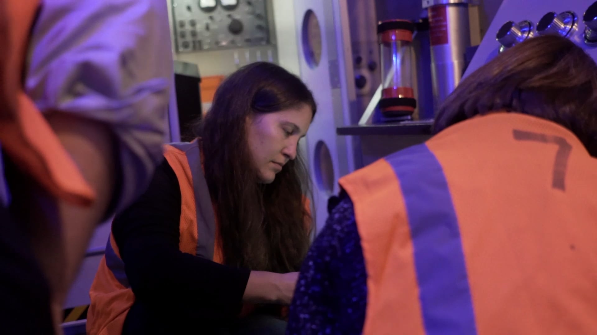 Workers in orange vests squat down as they plan their escape.