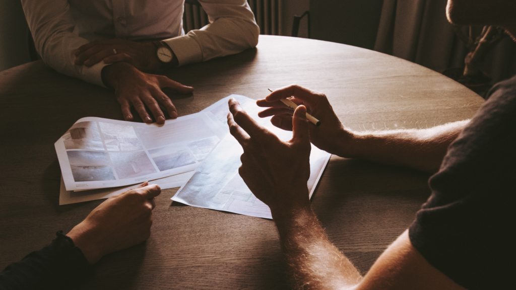 Three-person team at a table discussing printouts