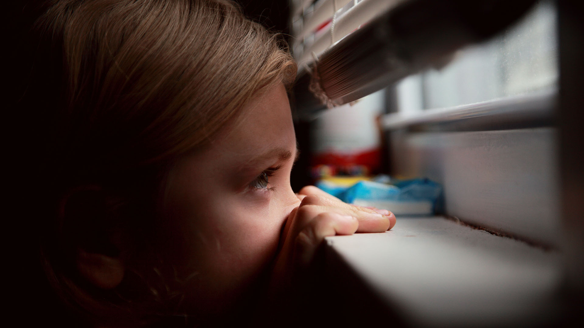 Girl looks out window during coronavirus self-quarantine