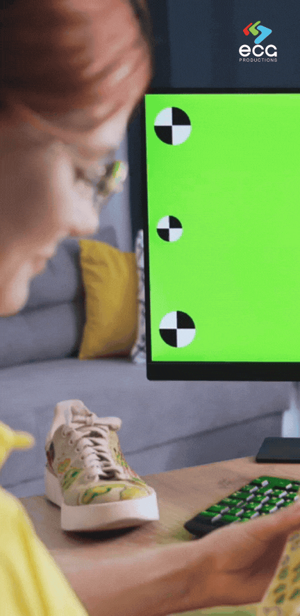 A woman examines a product while working with a green screen featuring tracking markers, demonstrating the precision required for planar tracking in visual effects