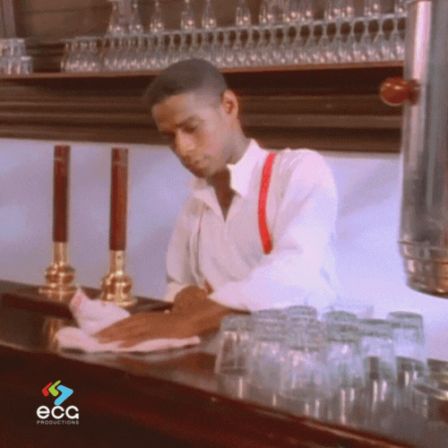 Bartender calmly polishing glasses in a quiet moment—adding contrast to the high-energy dance cuts in the now-legendary Rick Roll music video.