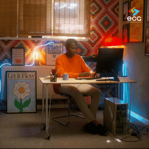 A young Black man works at a desk while the camera dollies in, emphasizing the importance of dolly grips in creating engaging, character-driven visuals.