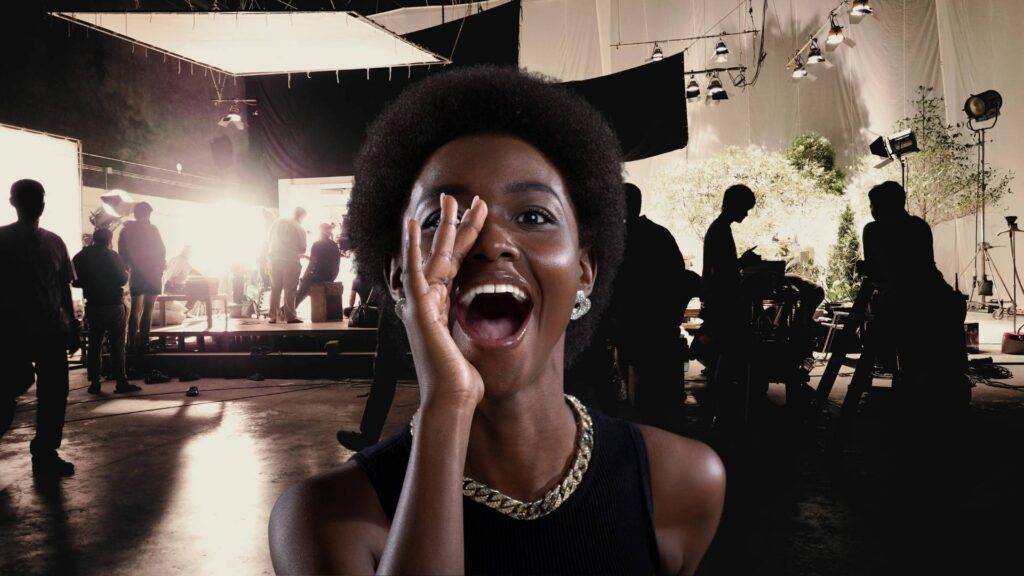 A black woman yells action on video production set