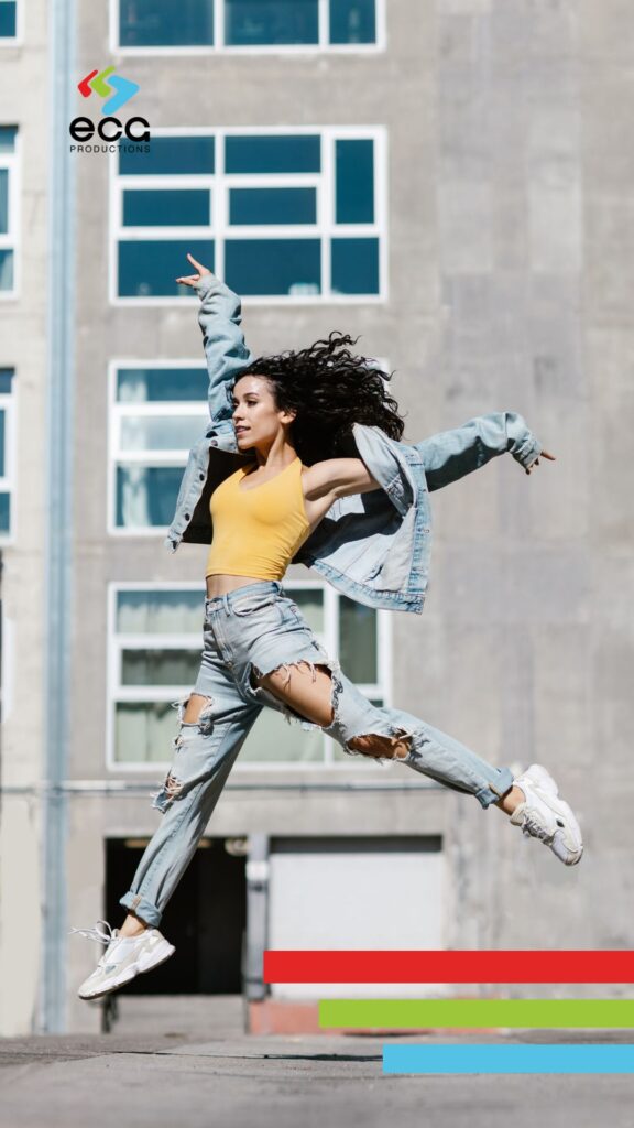 High Quality Video Production - Woman joyfully leaping into the air on a city sidewalk—capturing the vibrant energy and realism that live action brings to the conversation around animation vs live action.
