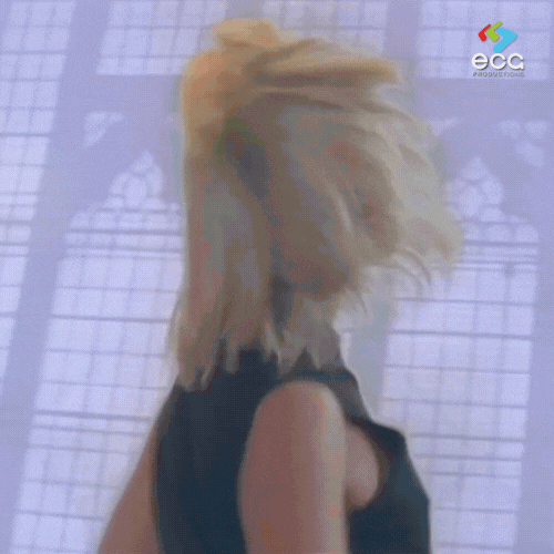 Blonde woman flipping her hair in slow motion against a backlit window—another quirky yet iconic frame from the music video at the heart of the history of the Rick Roll.