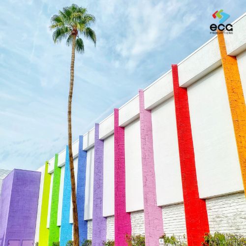 Modern building facade featuring dynamic multicolored lines beneath a clear blue sky with a large palm tree—illustrating how vibrant color schemes create mood and impact in TV commercials using color psychology.