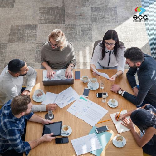 Diverse group of young professionals casually gathered, drinks in hand and one person showing content on a smartphone—capturing authentic moments that reflect learner engagement in training videos.