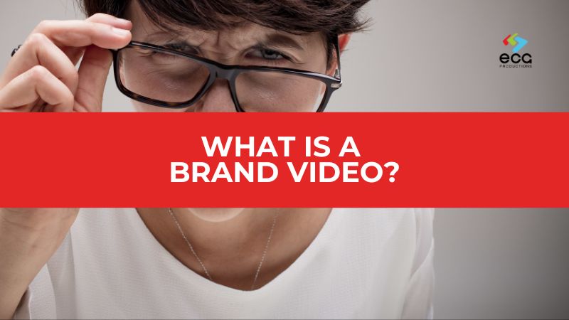 Confused-looking woman adjusting her glasses, with a bold red bar and white text reading “What is a Brand Video ?”—visually capturing the curiosity and need for clarity around brand video strategy.
