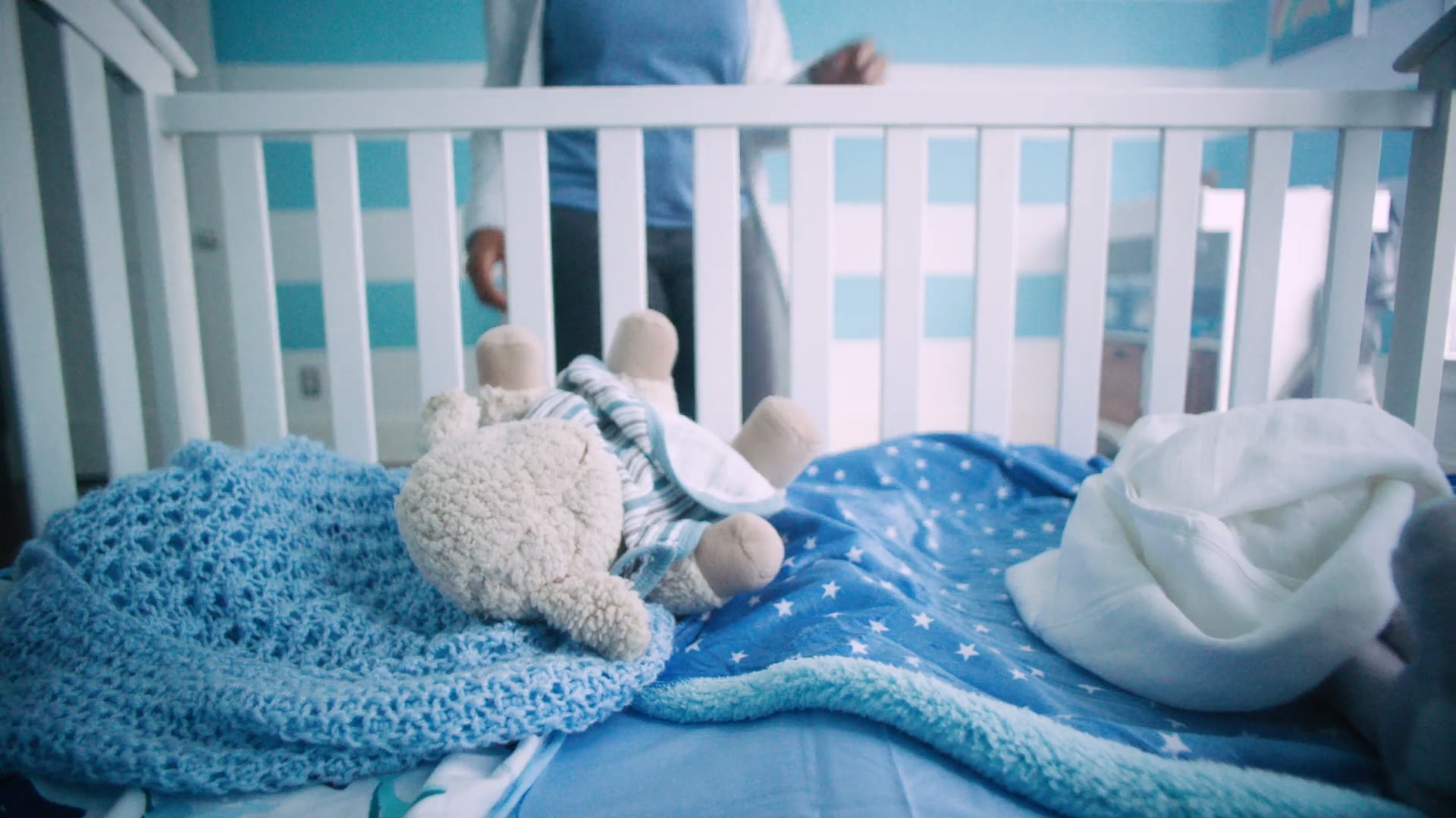 A woman approaches an empty baby crib