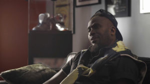 Anwan "Big G." Glover sits on a couch while filming some branded content for a mini-doc.
