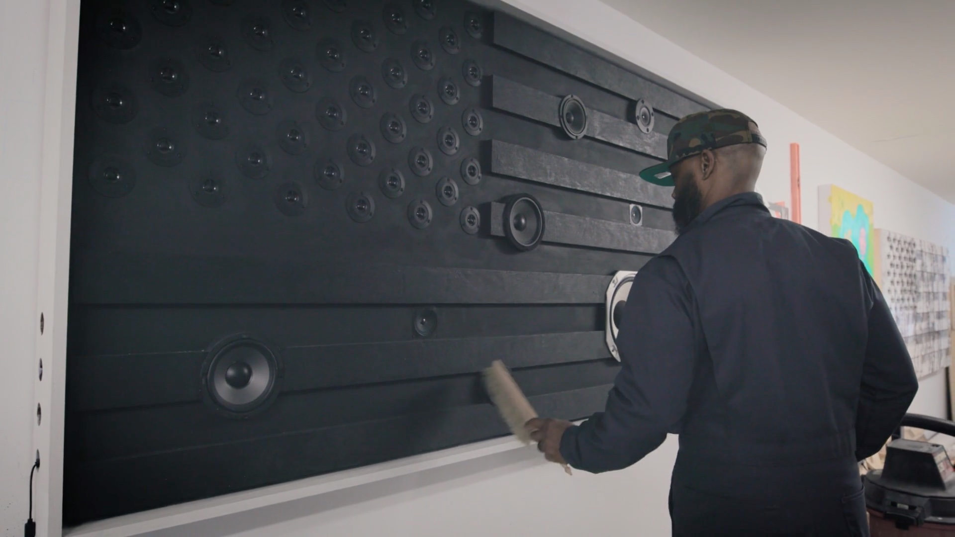 DL Warfield brushes off a black American flag composed of wood and speakers.