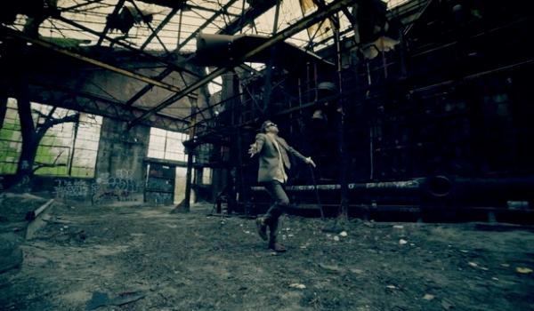 16 OS - 3's Company music video still of a man in a warehouse.