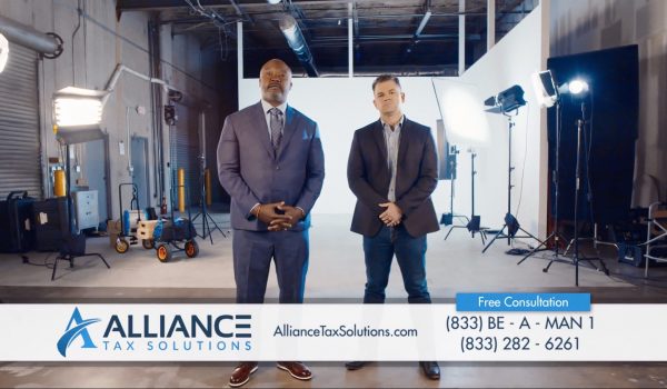 Two men from Alliance Tax Solutions break through the fourth wall.