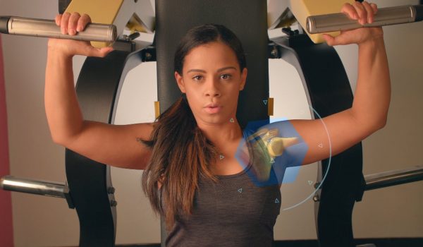 A woman stares into the camera while performing a no-excuses bench press.