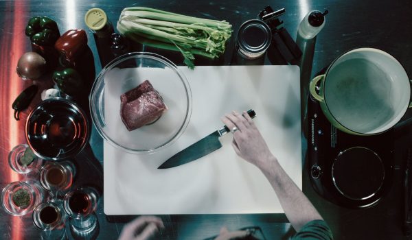 A bird's eye view of a chef grabbing a knife on a cutting board.